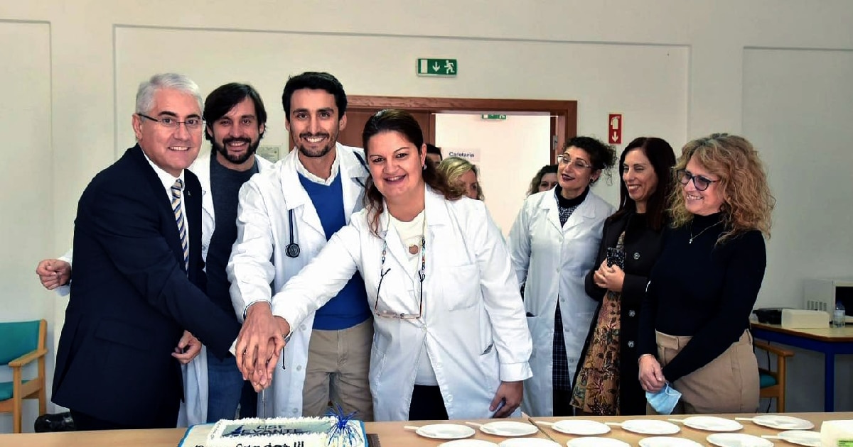 Profissionais de saúde celebrando com bolo em hospital.